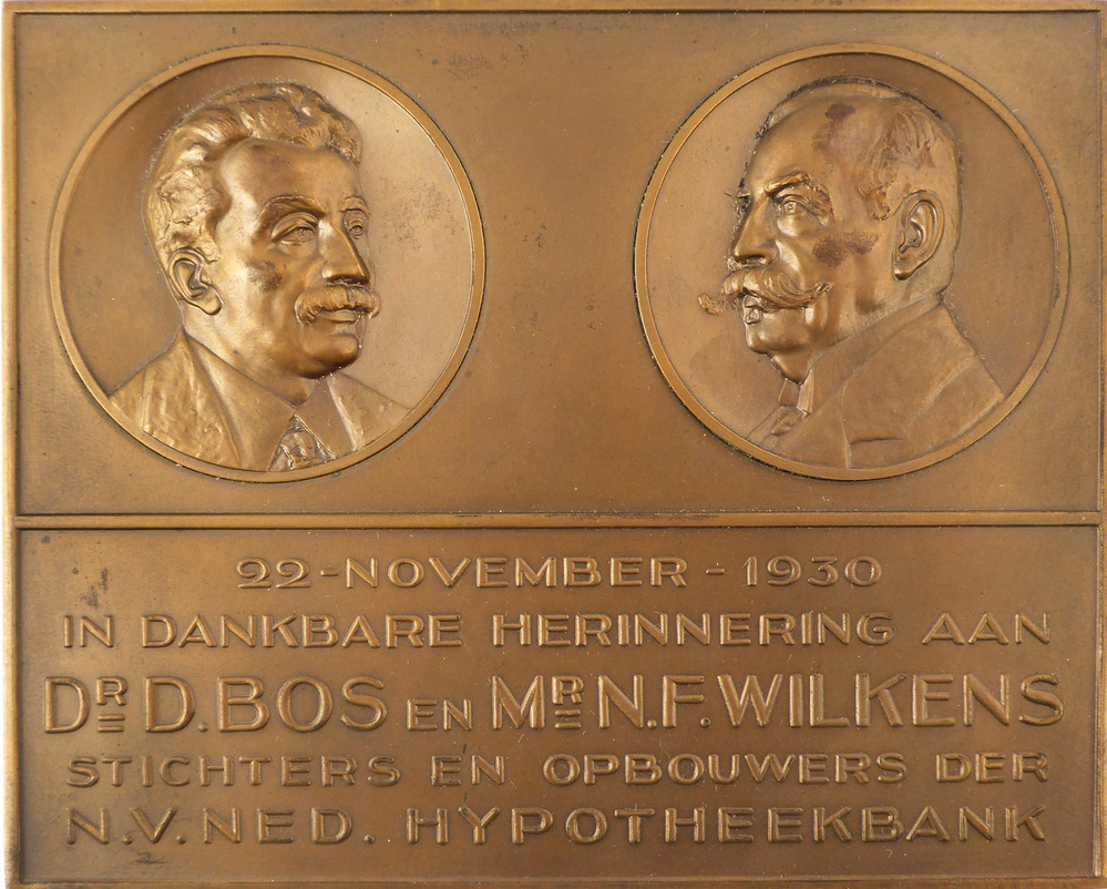 rechthoekige bronzen plak met opschrift : 22 november 1930 in dankbare herinnering aan Dr D. Bos en Mr N.F. Wilkens stichters en opbouwers der NV Ned Hypotheekbank, met aan weerszijden afbeelding hoofd van Dr. D. Bos en Mr. N.F. Wilkens
